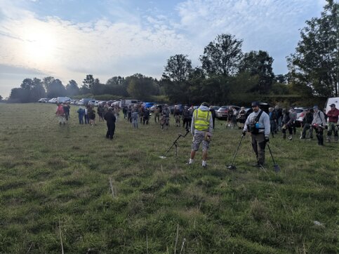 Group of metal detectorists spread out across a large open field